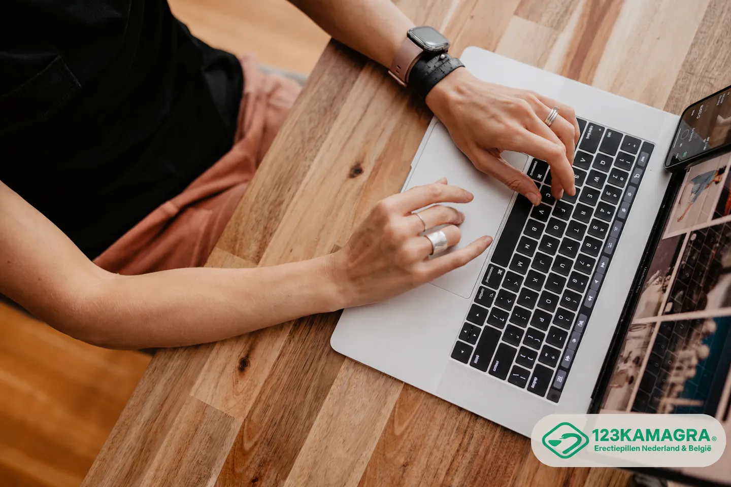 Handen bij een laptop op een houten tafel tijdens online gebruik